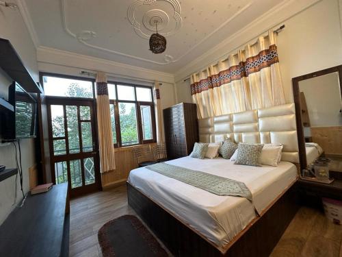 Maa Tara Anchal Cottage By BYOB Hotels في شيملا: غرفة نوم بسرير كبير وتلفزيون