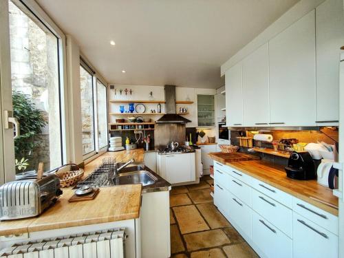 Home - Visitandines - Séjour à Auxerre في أوكسير: مطبخ مع دواليب بيضاء ونافذة كبيرة