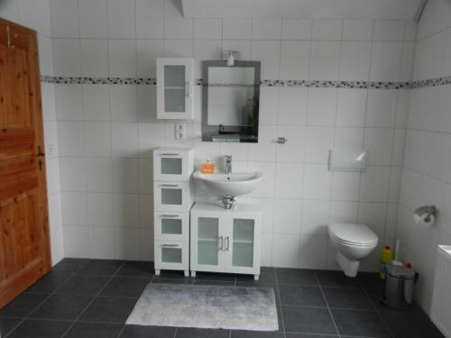 La salle de bains blanche est pourvue d'un lavabo et de toilettes. dans l'établissement Ferienwohnung Behrends, 15178, à Leer