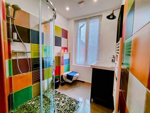 La salle de bains colorée est pourvue d'une douche et d'un lavabo. dans l'établissement Toit & Bois - Séjour à Auxerre, à Auxerre