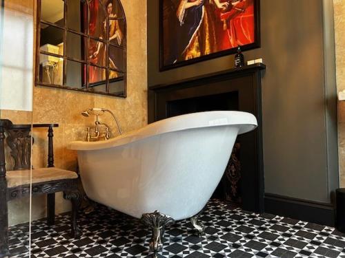 a white bath tub in a bathroom with a fireplace at Golden Fleece York in York