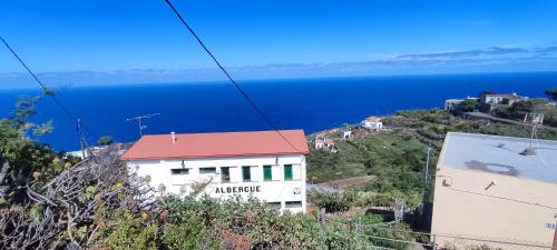 un edificio blanco en una colina junto al océano en Hostal Albergue Garafía El Tablado, en Tablado de la Montañeta