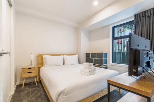 - une chambre blanche avec un lit et une fenêtre dans l'établissement Cozy apartment by Eden Park, à Auckland