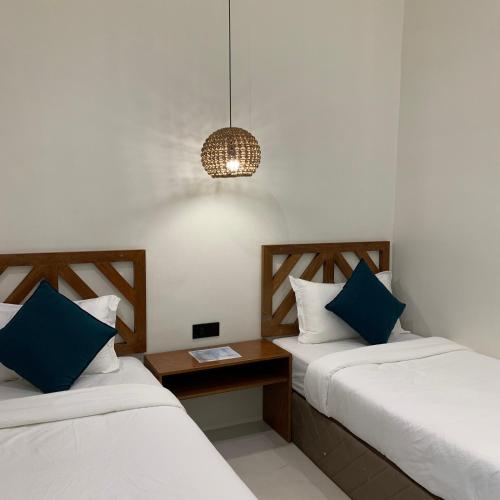 two beds in a room with a table and a lamp at Bahandi Hotel in General Luna