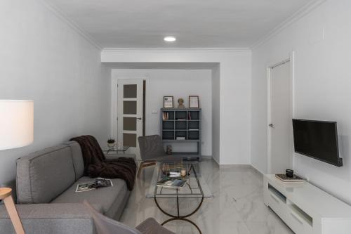 ein Wohnzimmer mit einem Sofa und einem TV in der Unterkunft tuGuest Alhamar Apartment in Granada