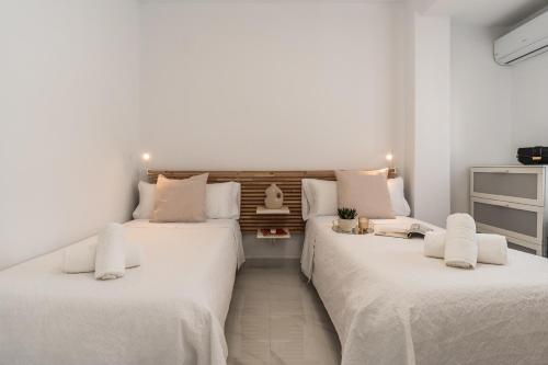 2 Betten in einem weißen Zimmer mit weißer Bettwäsche in der Unterkunft tuGuest Alhamar Apartment in Granada