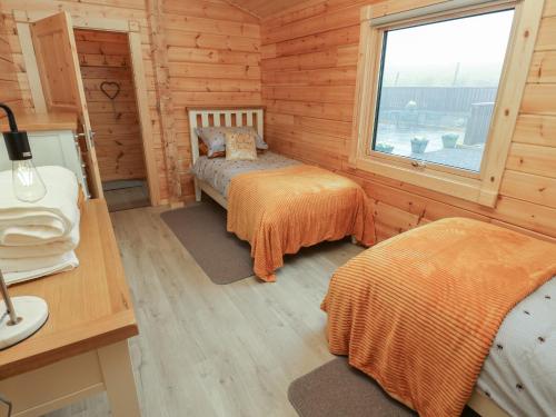 a bedroom with two beds in a wooden cabin at Height End Farm Log Cabin in Bacup
