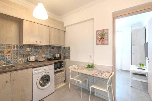 cocina con lavadora y mesa con sillas en Your perfect choice in Athen's best location, en Atenas