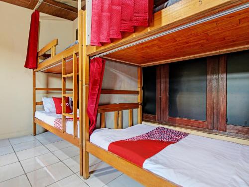 a bedroom with two bunk beds with red curtains at OYO 92851 Homestay Borobudur Specpacker Syariah in Yogyakarta