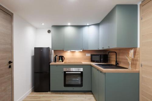 uma cozinha com armários azuis e um frigorífico preto em Jungle Room de Charme em Marselha