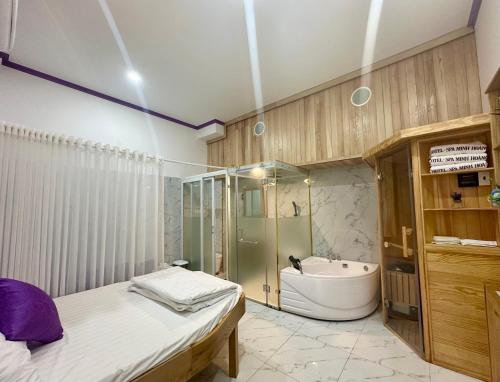 uma casa de banho com uma cama, uma banheira e um chuveiro em Minh Hoàng Hotel & Spa - Phan Thiết em Ấp Bình Hưng