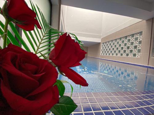 a vase with red roses next to a swimming pool at ANGKOR SIVUTHA HOTEL in Siem Reap