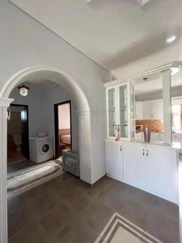 a kitchen with white cabinets and an archway at Villa Kapllani in Delvinë