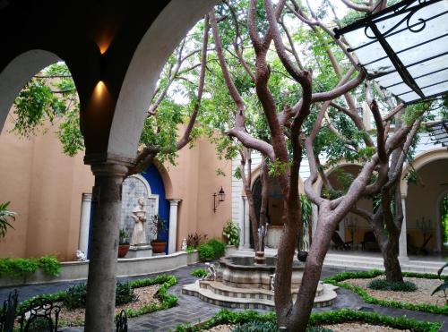 a courtyard with a fountain and a tree at Hotel Boutique La Mision De Fray Diego in Mérida