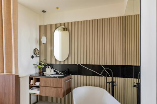 a bathroom with a tub and a sink and a mirror at Casa de las Artes, member of Meliá Collection in Madrid