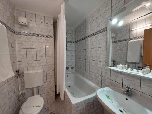 uma casa de banho com uma banheira, um WC e um lavatório. em Hotel Egreta em Tulcea