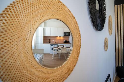 - un miroir en rotin suspendu sur un mur dans le salon dans l'établissement Le Cocon - Appart Neuf Clim Wifi 2 à 4 personnes, à Marseille