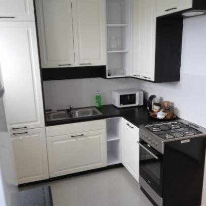 La cuisine est équipée de placards blancs et d'un four avec plaques de cuisson noires. dans l'établissement Hostel Reja 54A, à Suwałki
