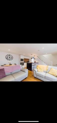 a living room with two white couches and a kitchen at The Hideout, Braunton, Devon in Braunton