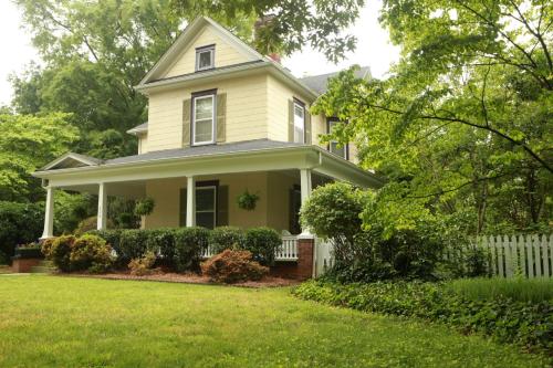 a yellow house with a white fence in a yard at The Dailey Renewal Retreat B & B in Greensboro