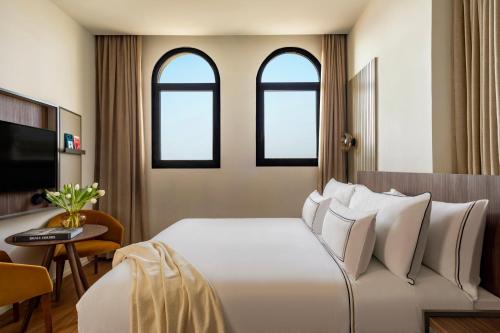 a bedroom with a large white bed with three windows at Casa de las Artes, member of Meliá Collection in Madrid