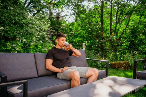 a man sitting on a couch drinking a drink at Amantis Vital Sport Hotel in Desná