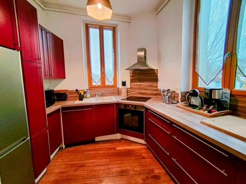 a kitchen with red cabinets and a sink at Home - L'Auxerroise - Séjour à Auxerre in Auxerre