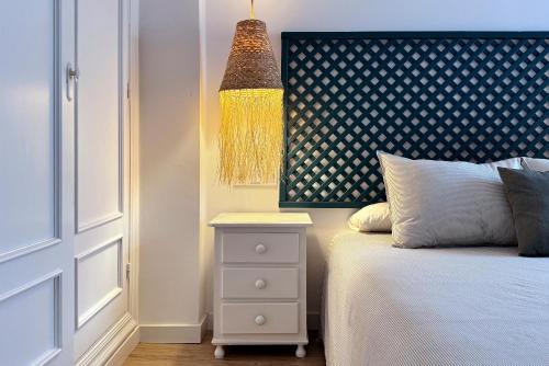 a bedroom with a bed with a night stand and a lamp at Apartamentos Vela Blanca in San José