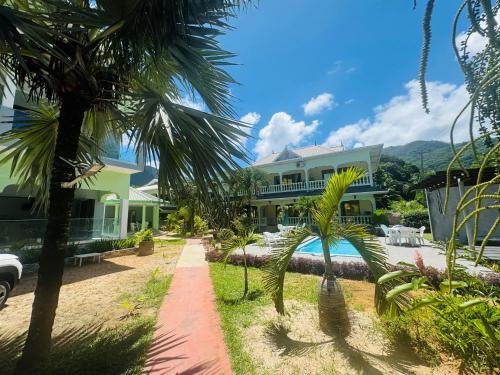 a large house with palm trees in front of it at Green Palm Self Catering in Anse aux Pins