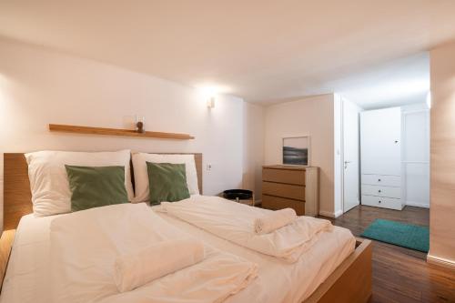 sypialnia z dużym łóżkiem z białą pościelą i zielonymi poduszkami w obiekcie D35 Boutique Apartments, Best Location by BQA w Budapeszcie