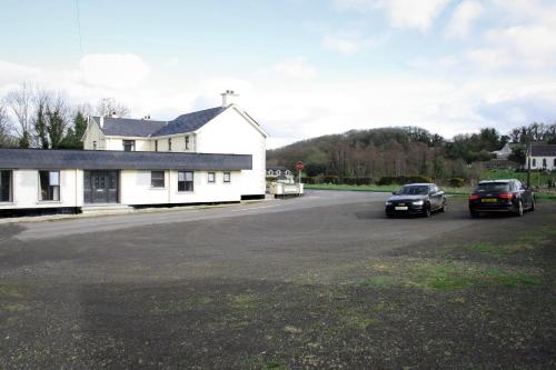 two cars parked on a road next to a white house at The Coach Inn in Strabane