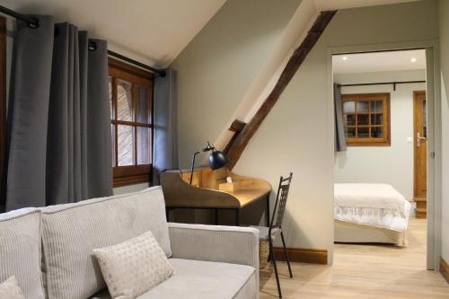 a living room with a couch and a desk and a bed at La Chaumière Normande in Vattetot-sous-Beaumont