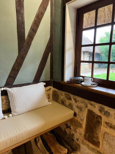 a bench in a room with two windows at La Chaumière Normande in Vattetot-sous-Beaumont