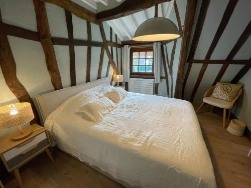 ein Schlafzimmer mit einem weißen Bett in einem Zimmer mit Balken in der Unterkunft La Chaumière Normande 