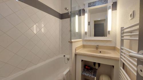 une salle de bain avec un lavabo, un miroir et une baignoire dans l'établissement Appartement Lacanau entre Golf et Océan pour 4 personnes, à Lacanau