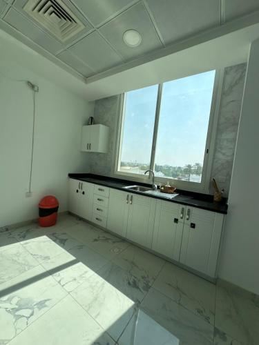 a white kitchen with a sink and a large window at Single room with window near metro in Dubai