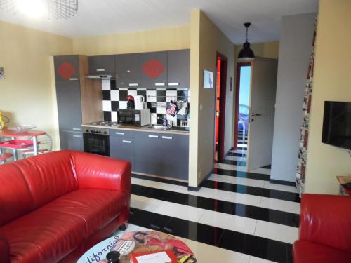a living room with a red couch and a kitchen at Guest house Western-city in Chaudfontaine