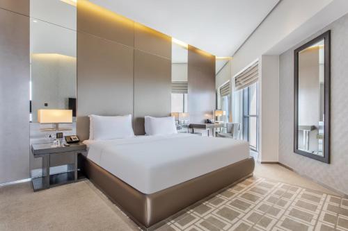 a bedroom with a large white bed and a desk at Spacious Studio Apartment in Hyatt Regency Dubai Creek Heights by the S Holiday Homes in Dubai