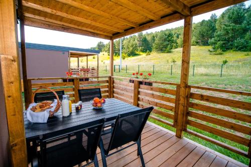a table on a deck with a view of a field at Big Bear Plitvice Nature Resort in Donji Babin Potok
