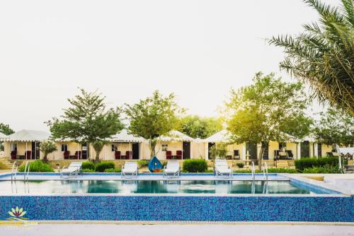 een zwembad in een resort met stoelen en bomen bij Mughal Sam Sand Dunes Desert Safari in Sām