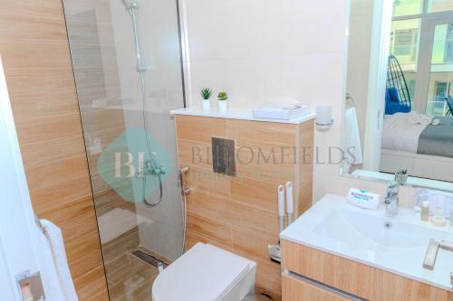 uma casa de banho com um chuveiro, um WC e um lavatório. em Modern 1 Bedroom In Oasis2 em Abu Dhabi