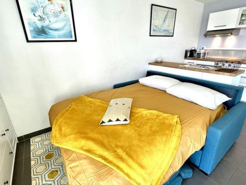 a bedroom with a bed with a yellow blanket on it at Très joli T2 en face du plan d'eau d'ETEL in Étel