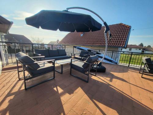 a patio with a couch and chairs and an umbrella at Villa Nova in Hévíz