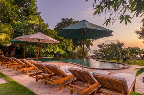 a group of chairs and umbrellas next to a swimming pool at Villa Sky Dancer - Bali in Amed