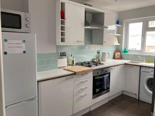 a kitchen with white cabinets and a stove top oven at Modern home for those on business or on holiday in Newport