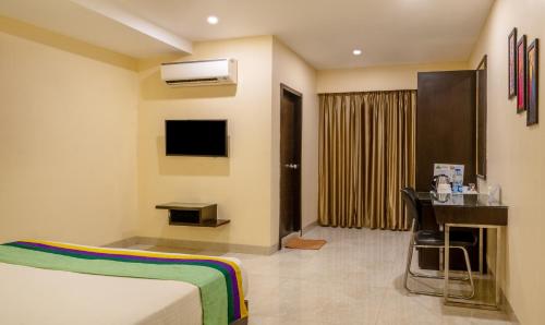 a hotel room with a bed and a desk and a television at Treebo Acsys, Gachibowli in Hyderabad