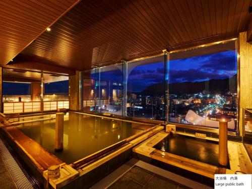 a swimming pool in a building with a view of a city at La Vista Hakodate Bay Annex in Hakodate