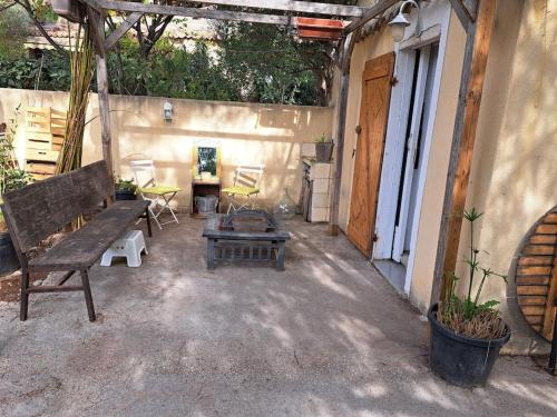 un patio con un banco de madera y una mesa en Studios sur CARRY le ROUET, en Carry-le-Rouet