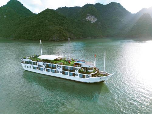 un bateau sur l'eau avec des montagnes en arrière-plan dans l'établissement Le Journey Calypso Pool Cruise Ha Long Bay, à Hạ Long