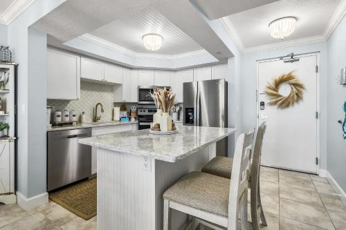 une cuisine avec des placards blancs et un comptoir avec des chaises dans l'établissement Beach Villas # 505 - BOGO24 condo, à Fort Myers Beach